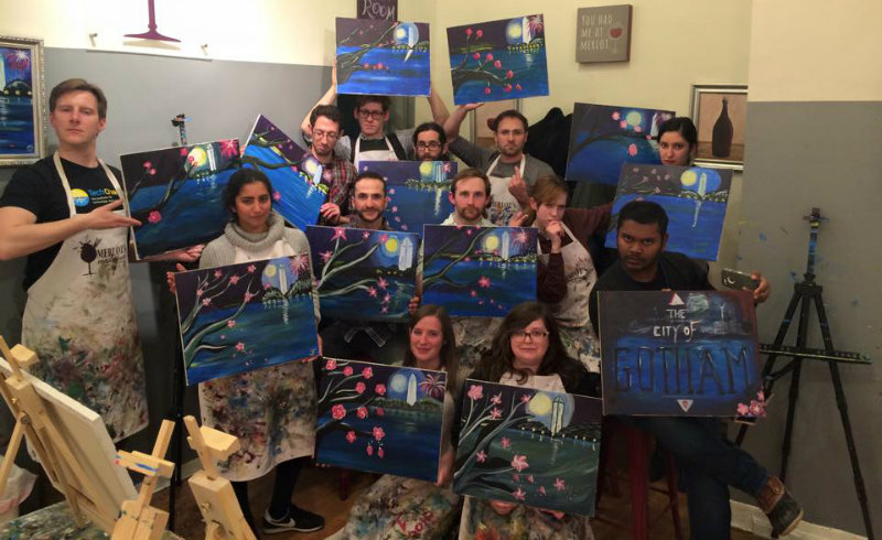 The TechChange team strikes a serious artist pose with their final art pieces during Wine and Painting night 